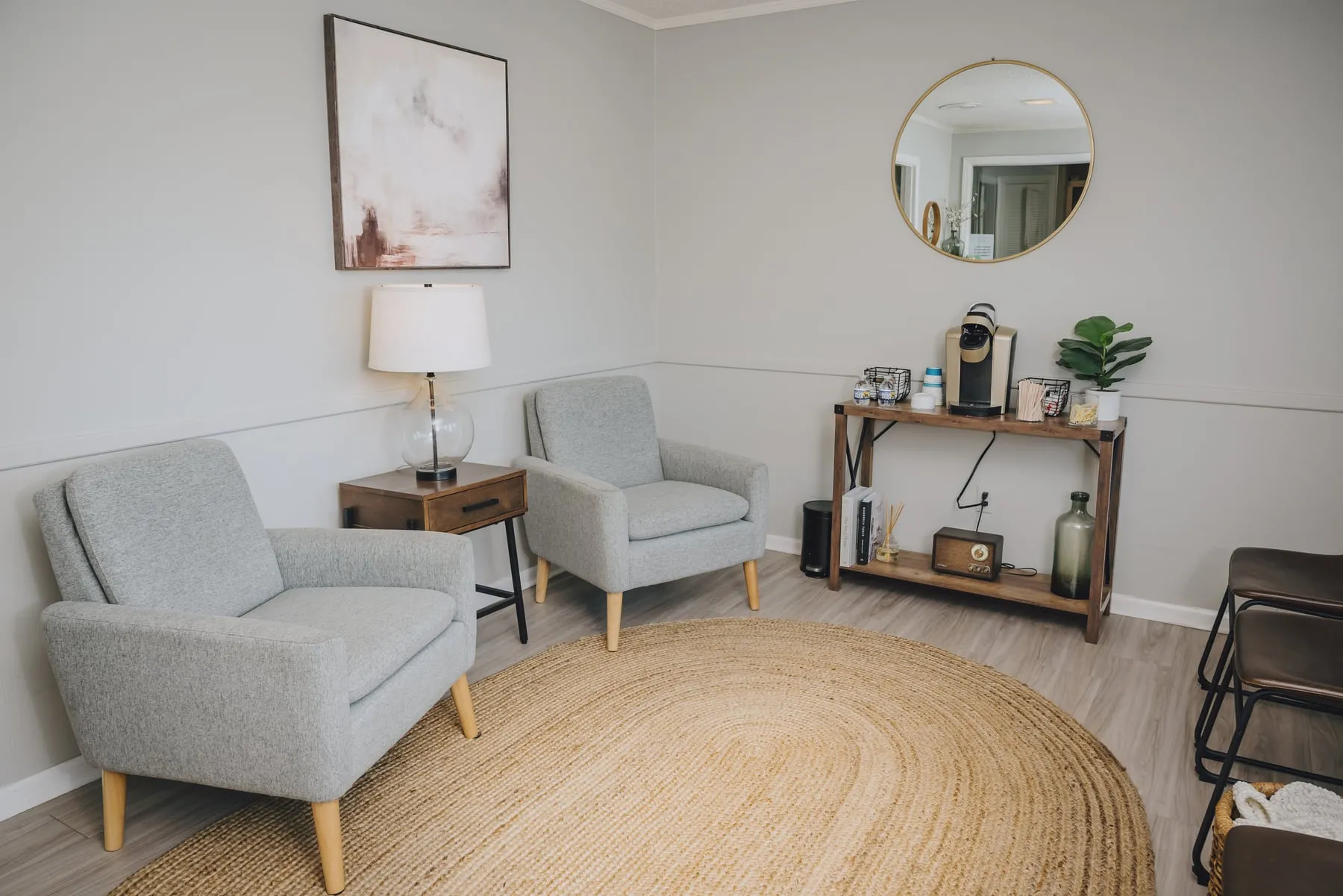 The waiting room at the Indigo Dentistry West office in West Columbia, with grey armchairs, a jute rug and a coffee station